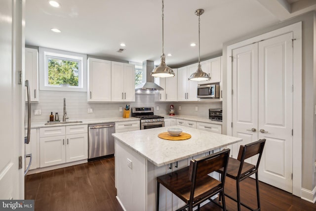 kitchen with stainless steel appliances, a kitchen island, white cabinetry, a breakfast bar area, and extractor fan