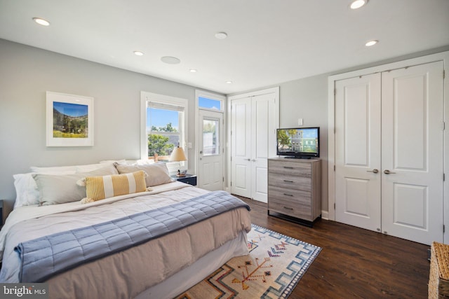 bedroom with multiple closets and dark hardwood / wood-style floors