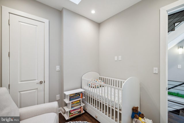 bedroom with a crib and dark hardwood / wood-style floors