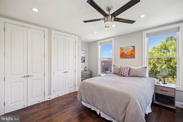 bedroom with ceiling fan, dark hardwood / wood-style floors, and multiple closets