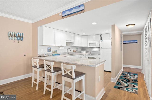 kitchen featuring kitchen peninsula, sink, white appliances, and white cabinetry