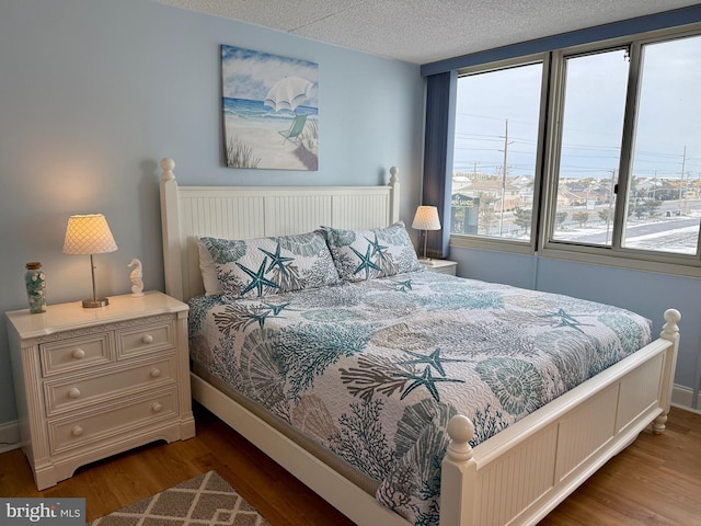 bedroom featuring hardwood / wood-style flooring, multiple windows, and a textured ceiling