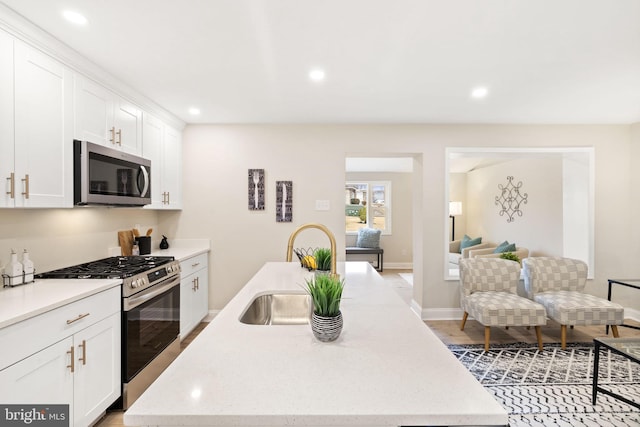 kitchen featuring sink, stainless steel appliances, white cabinets, and a center island with sink