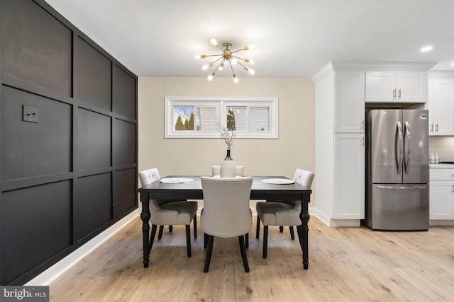 dining area with light hardwood / wood-style floors and a notable chandelier