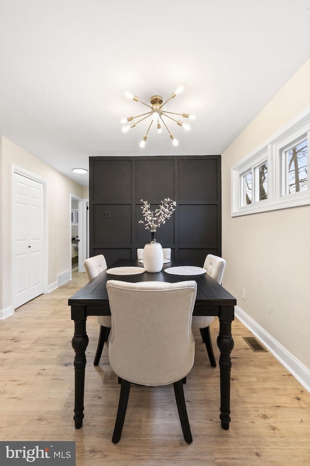 dining space featuring light wood-type flooring and a chandelier