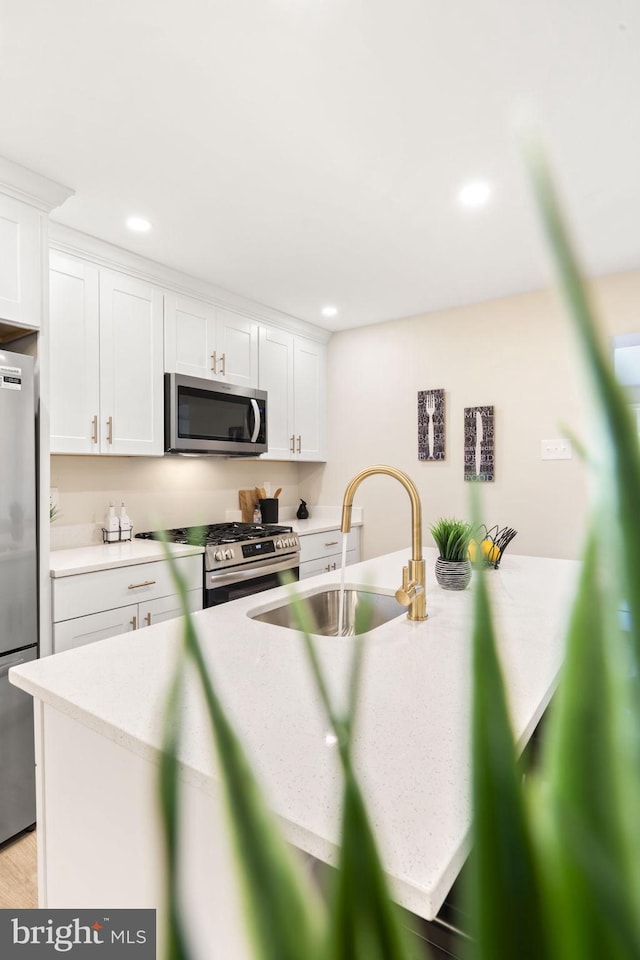 kitchen featuring sink, white cabinetry, light hardwood / wood-style flooring, and appliances with stainless steel finishes