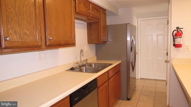 kitchen with a textured ceiling, light tile patterned floors, stainless steel dishwasher, and sink