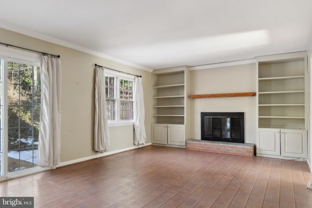 unfurnished living room featuring a wealth of natural light, a brick fireplace, hardwood / wood-style floors, and crown molding