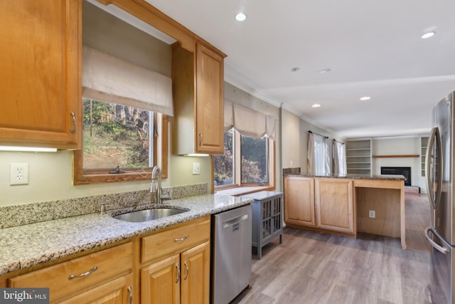 kitchen featuring sink, light wood-type flooring, ornamental molding, appliances with stainless steel finishes, and light stone countertops