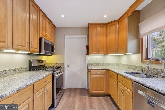 kitchen featuring light stone counters, sink, light wood-type flooring, and appliances with stainless steel finishes