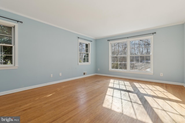 spare room featuring crown molding and light hardwood / wood-style floors