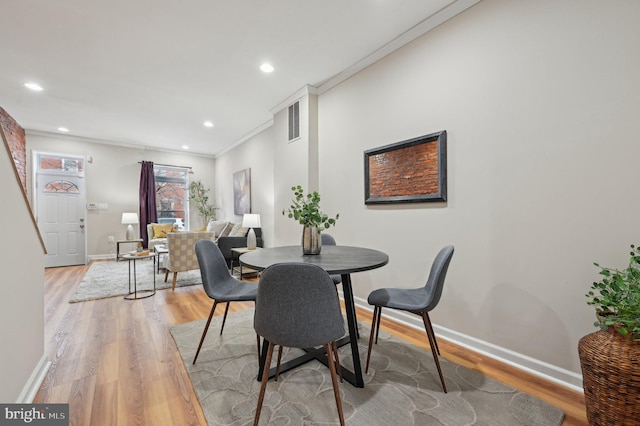 dining space featuring crown molding and light wood-type flooring