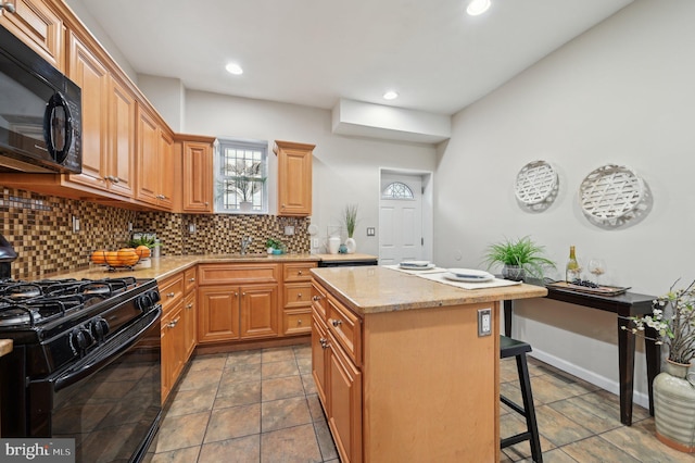 kitchen with backsplash, a center island, black appliances, light stone countertops, and a breakfast bar area