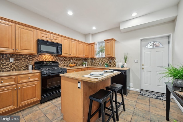 kitchen featuring a kitchen bar, backsplash, black appliances, and a center island