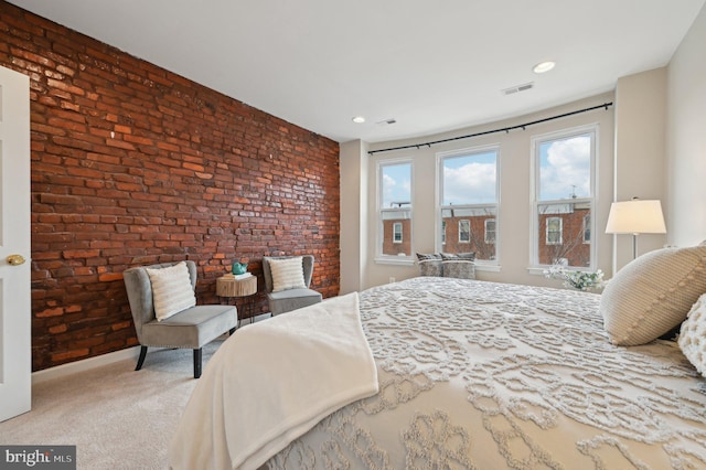 bedroom with brick wall and light colored carpet