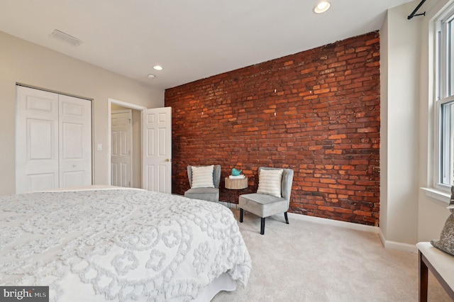 bedroom featuring light carpet, a closet, brick wall, and multiple windows