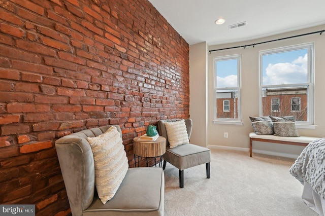 sitting room featuring light colored carpet and brick wall