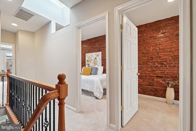 hall with light colored carpet and brick wall