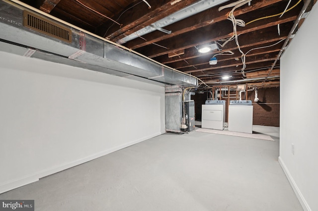 basement featuring heating unit and washer and clothes dryer