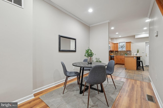 dining room with crown molding and light hardwood / wood-style floors