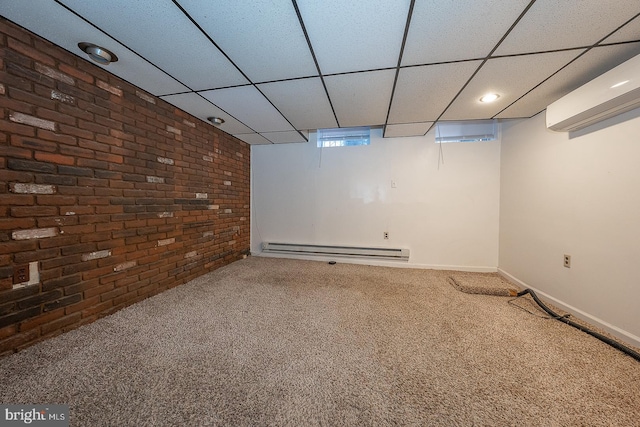 basement with baseboard heating, an AC wall unit, carpet floors, brick wall, and a drop ceiling