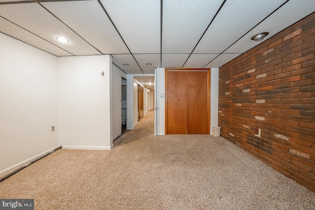 spare room with carpet flooring, brick wall, and a paneled ceiling