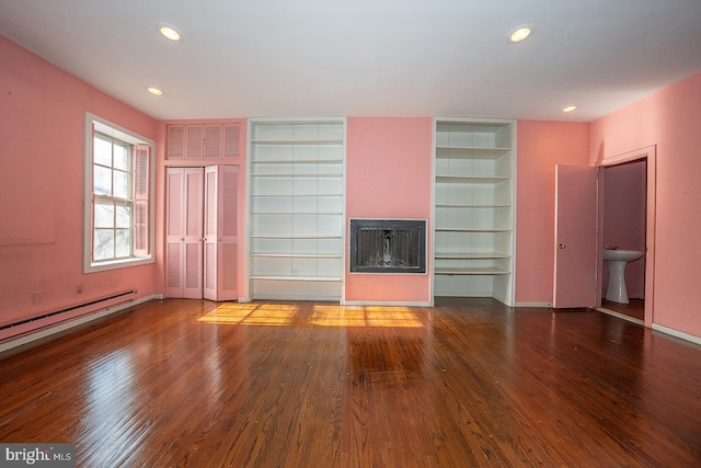 unfurnished living room with a baseboard heating unit and hardwood / wood-style floors