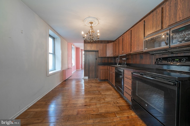 kitchen with black appliances, a notable chandelier, dark hardwood / wood-style floors, and sink