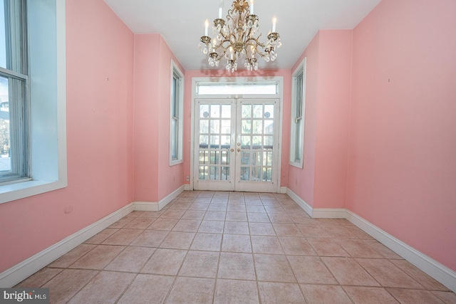 tiled spare room featuring an inviting chandelier and french doors