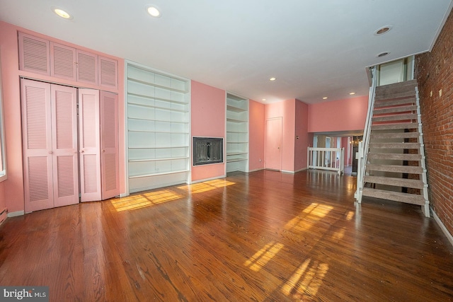 unfurnished living room featuring brick wall and wood-type flooring