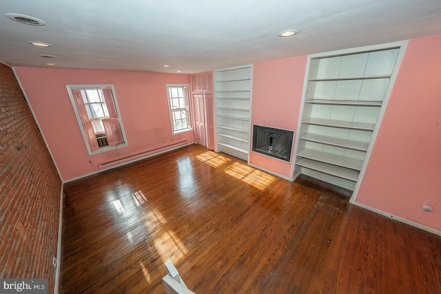 unfurnished living room with brick wall, wood-type flooring, a baseboard heating unit, and heating unit