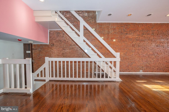 stairway with brick wall and wood-type flooring