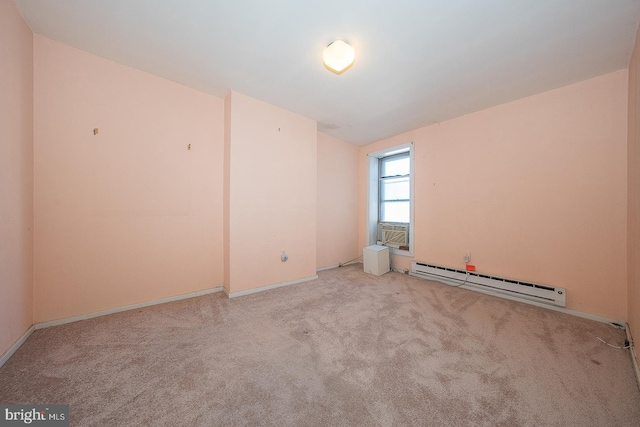 spare room featuring a baseboard heating unit and light carpet