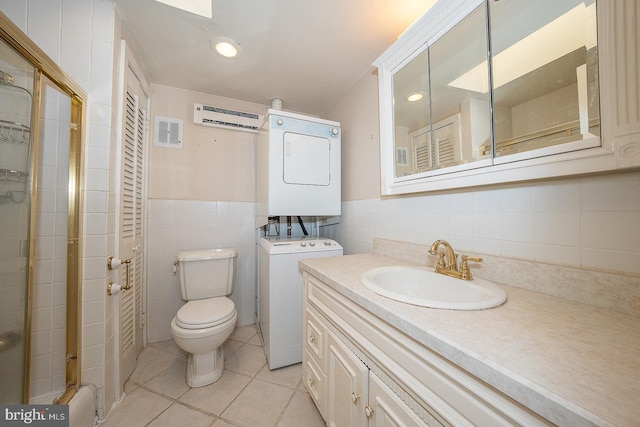 bathroom featuring toilet, tile patterned flooring, tile walls, stacked washer and clothes dryer, and vanity