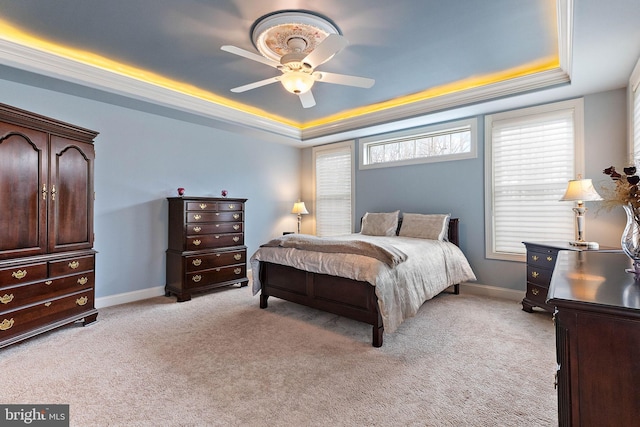 carpeted bedroom with a raised ceiling, ceiling fan, and crown molding