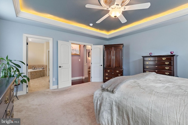 carpeted bedroom with ensuite bath, ceiling fan, and a tray ceiling