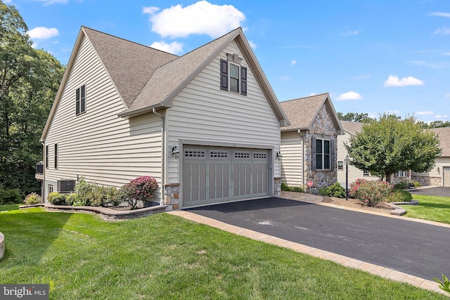 view of front of home with a garage, central AC, and a front lawn