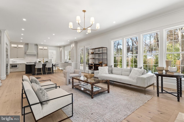 living room with light hardwood / wood-style flooring, crown molding, and a chandelier