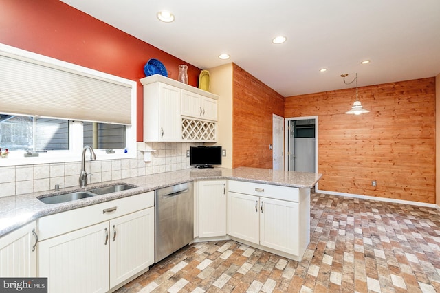 kitchen with white cabinets, kitchen peninsula, sink, decorative light fixtures, and stainless steel dishwasher