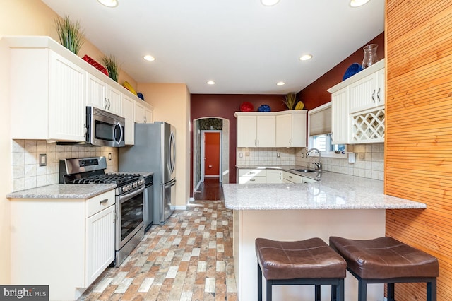 kitchen with appliances with stainless steel finishes, a breakfast bar, white cabinets, and kitchen peninsula