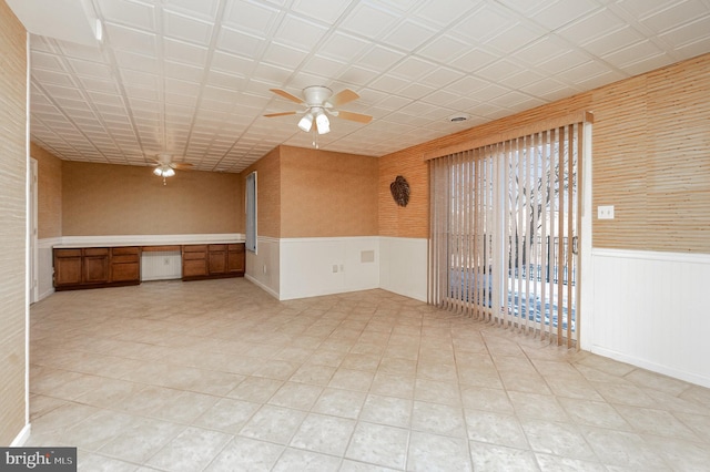 unfurnished room with built in desk and ceiling fan