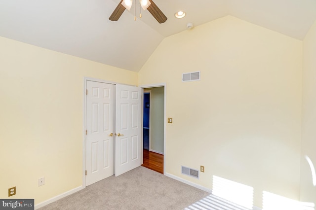 unfurnished bedroom with a closet, ceiling fan, vaulted ceiling, and light colored carpet