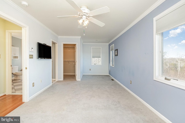 unfurnished bedroom featuring multiple windows, ceiling fan, crown molding, and light colored carpet