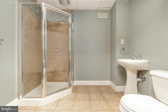 bathroom with toilet, a shower with door, and tile patterned floors