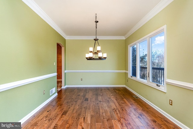 unfurnished dining area featuring dark hardwood / wood-style flooring, crown molding, and a chandelier