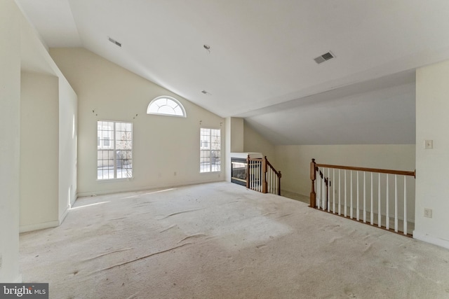 additional living space featuring light colored carpet and vaulted ceiling