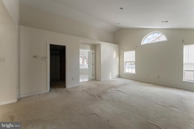 unfurnished room with light colored carpet, a wealth of natural light, and lofted ceiling