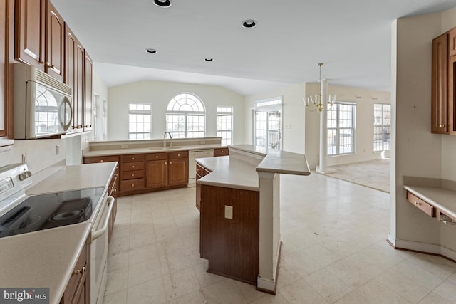 kitchen featuring an inviting chandelier, decorative light fixtures, white appliances, lofted ceiling, and a center island