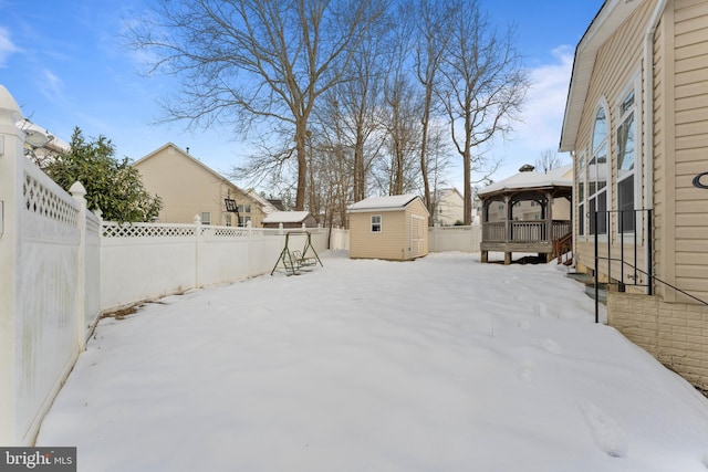 yard covered in snow with a gazebo and a storage shed