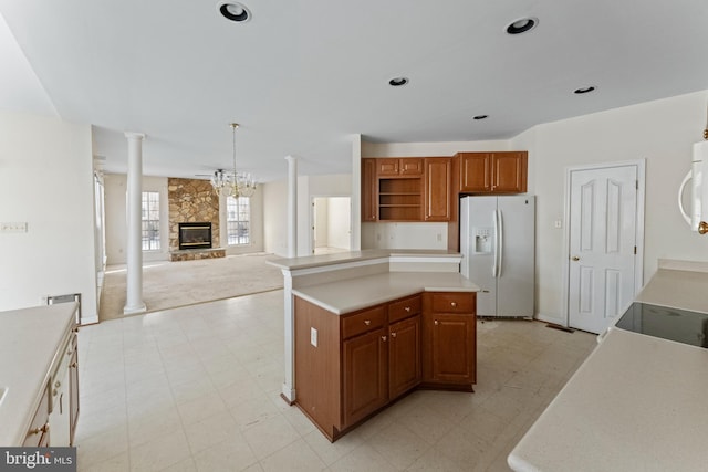 kitchen with white appliances, a kitchen island, a stone fireplace, an inviting chandelier, and hanging light fixtures